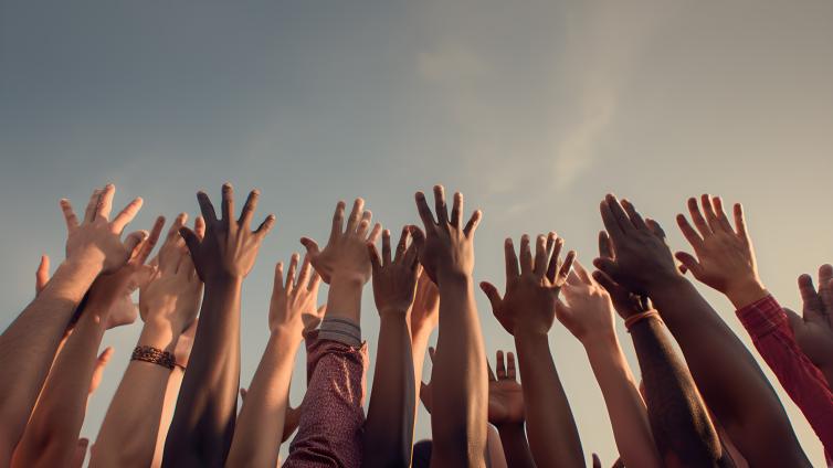 Photo of a group of arms reaching up towards the sky